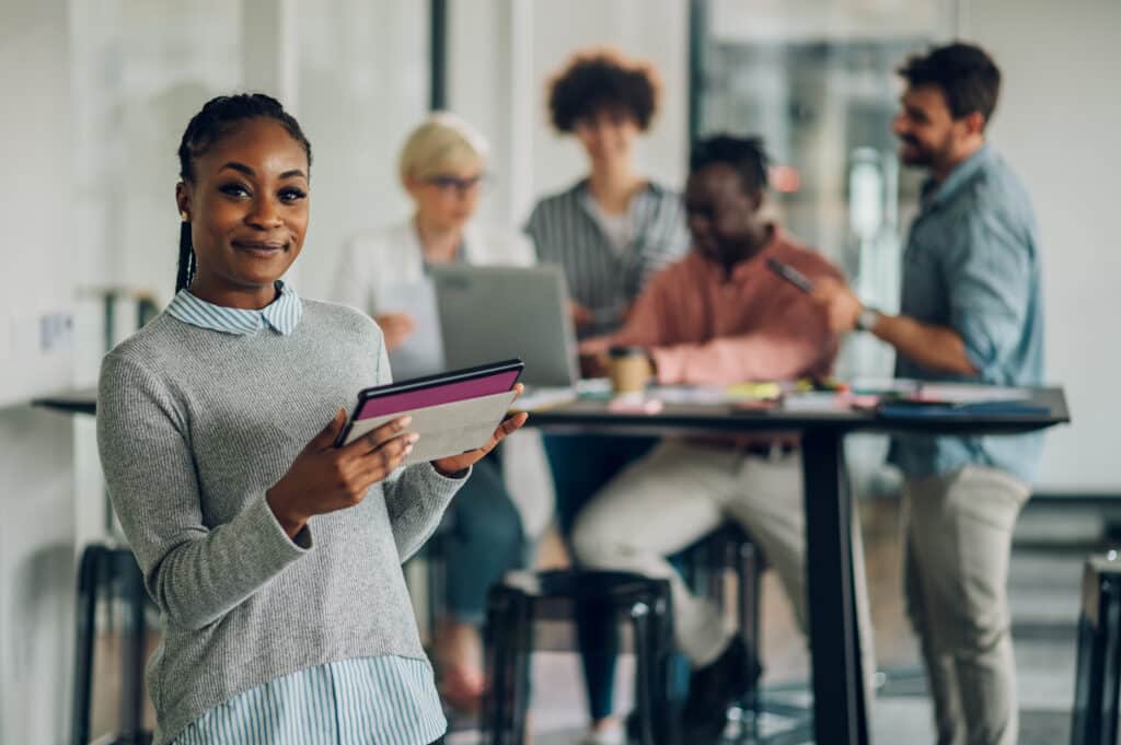 African american business woman standing in a office with collea