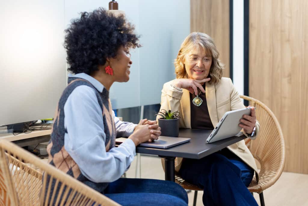 Business women collaborating on tablet in office meeting