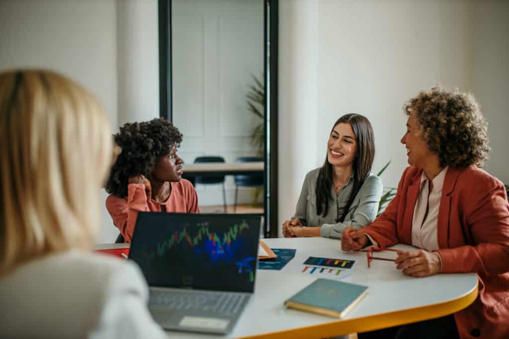 Businesswomen having a meeting discussing stock market charts on laptop