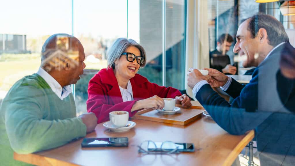 Friends chatting, enjoying coffee at small urban cafe table
