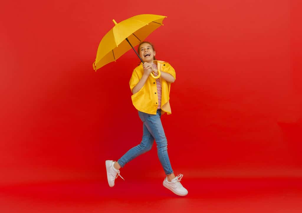 Kid with umbrella on colored background.