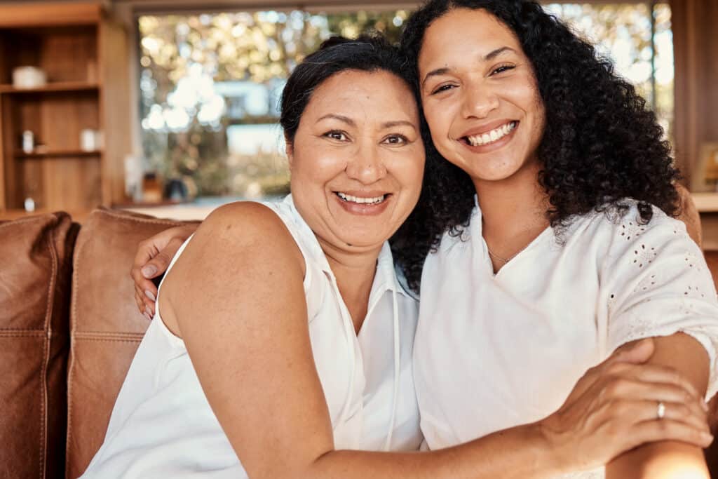 two-smiling-women-embracing-indoors-on-a-brown-sof-2026-03-25-02-20-42-utc